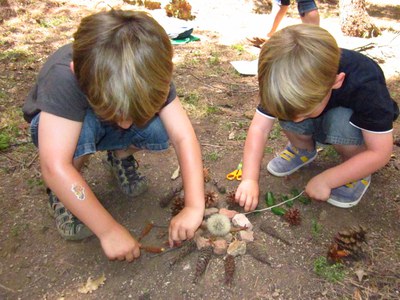 Niños construyendo un mandala con elementos naturales.